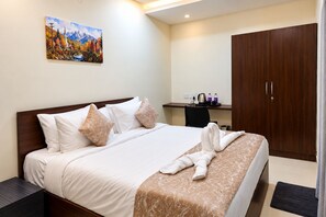 Habitación de hotel con cama, almohadas, un cuadro en la pared, escritorio con silla y armario.