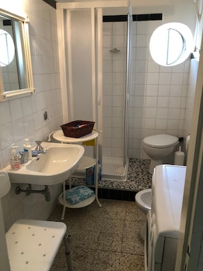 A compact bathroom with a sink, toilet, and shower. - Vrbo Property (Liguria)