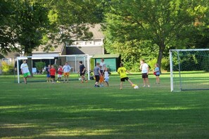 Ein Fußballfeld mit Toren, einem Netz und Spielern in Sportkleidung.