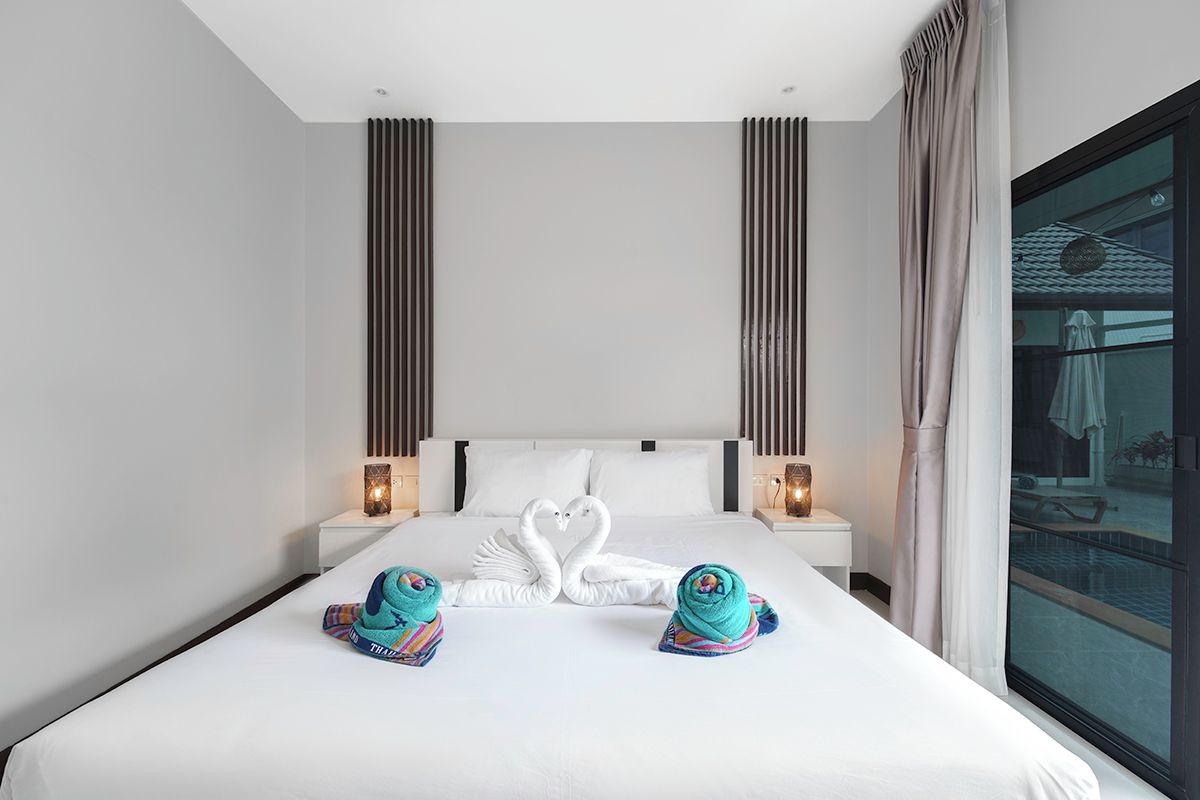 A hotel room with a large bed, two nightstands, a window with a view of a pool, and towels arranged in a swan shape.