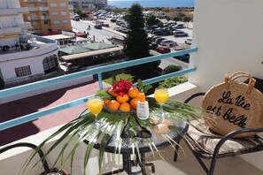 Ein Balkon mit Frühstückstisch, einem Korbwäscher und Blick auf einen Parkplatz sowie Gebäude.
