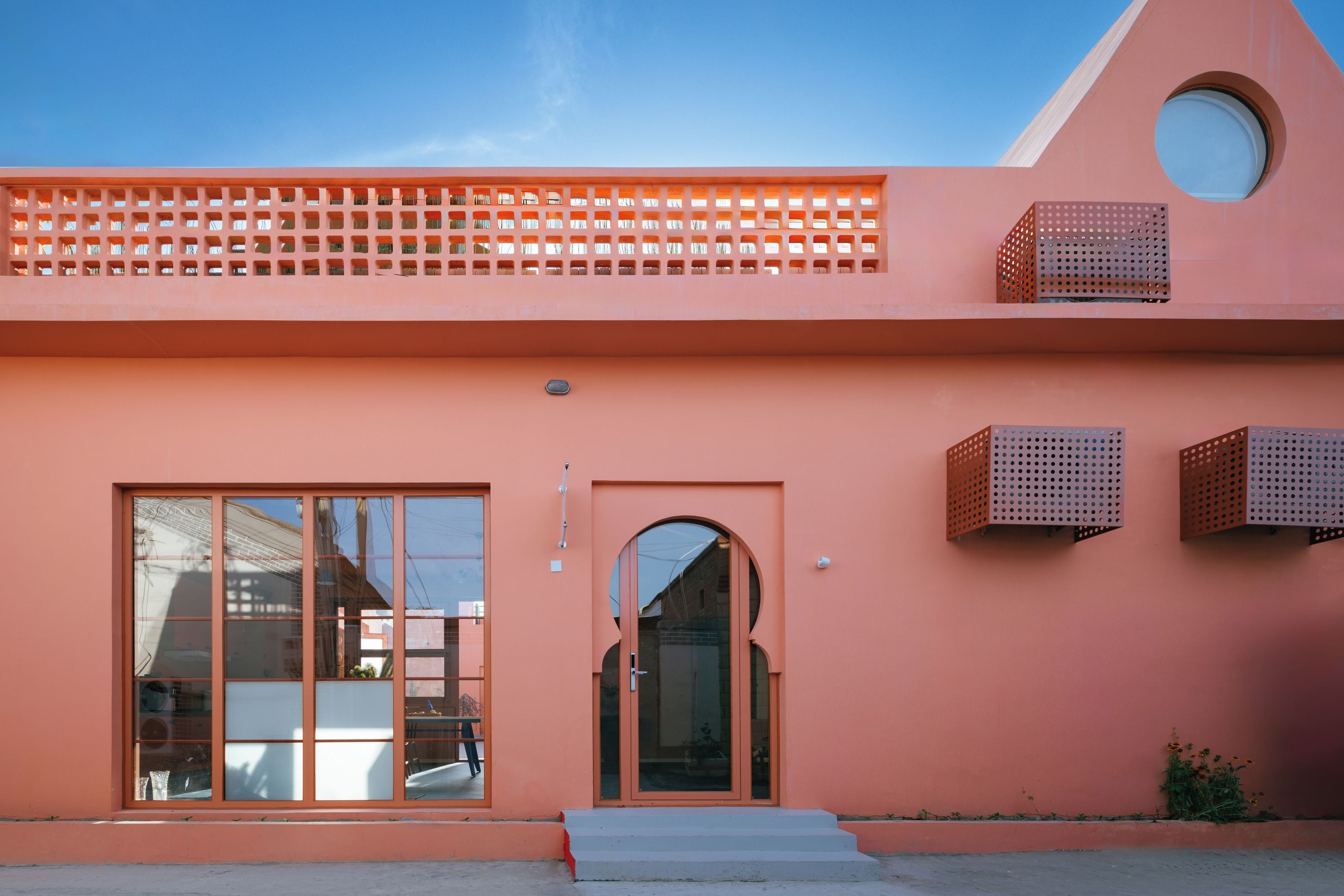 A building with a pink facade, large windows, and a small entrance.