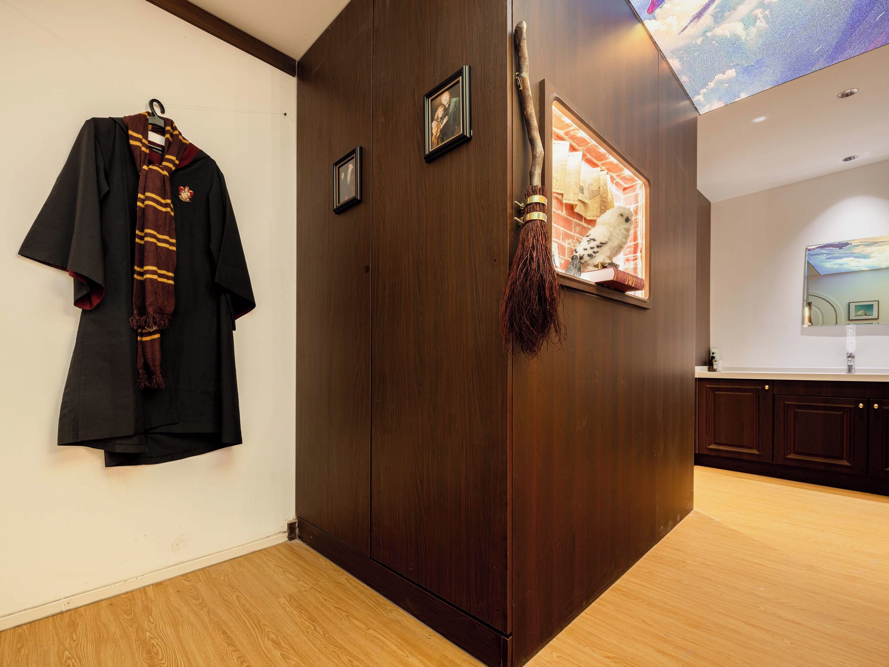A room with a wooden wardrobe, a coat hanging on the wall, and a framed picture.
