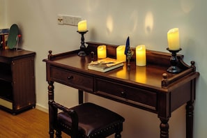 A wooden desk with four lit candles, a book, and a quill pen.