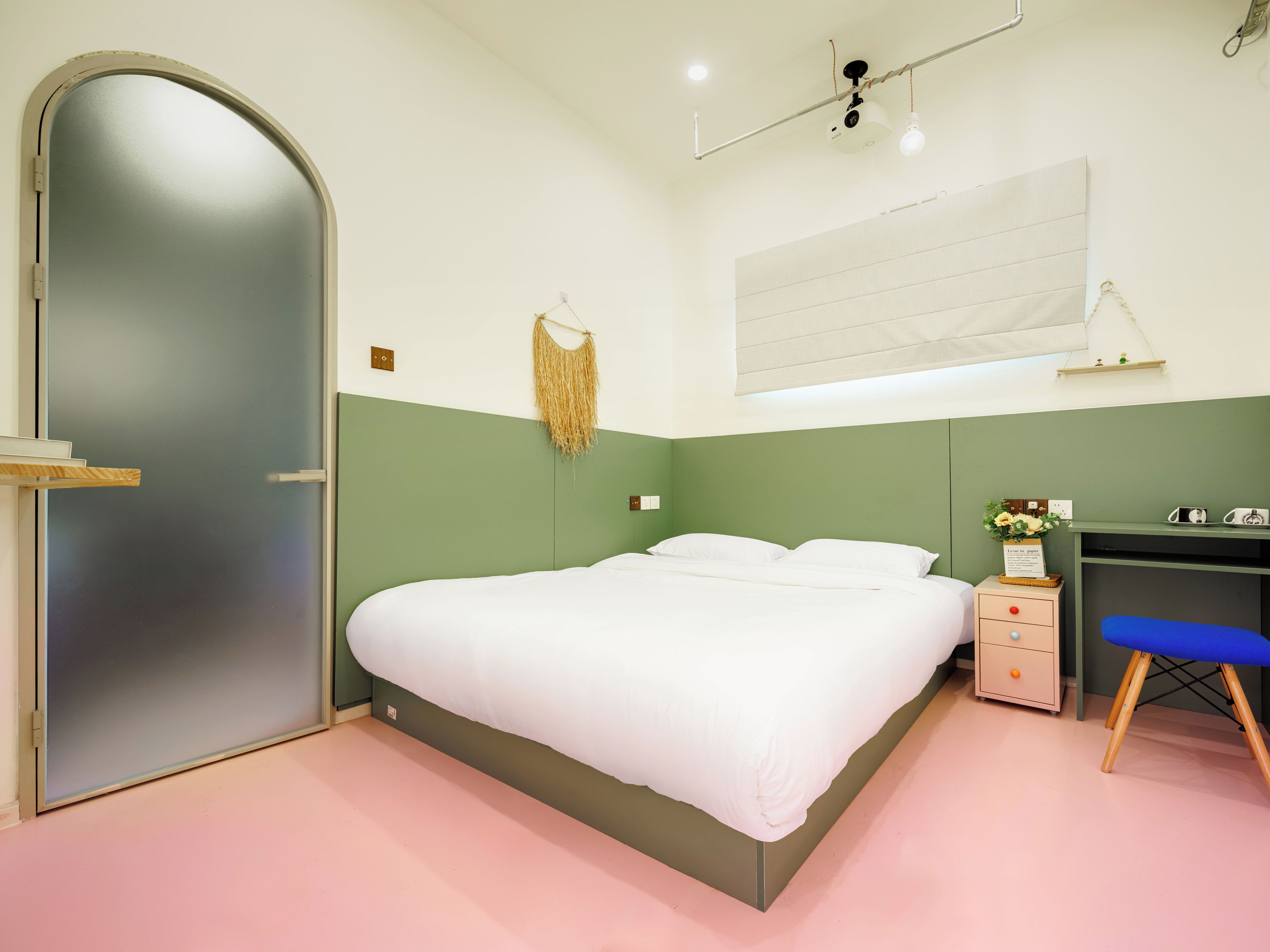 A bedroom with a bed, a desk, a chair, and a door.