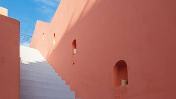 A staircase leading up to a building with pink walls and small windows.