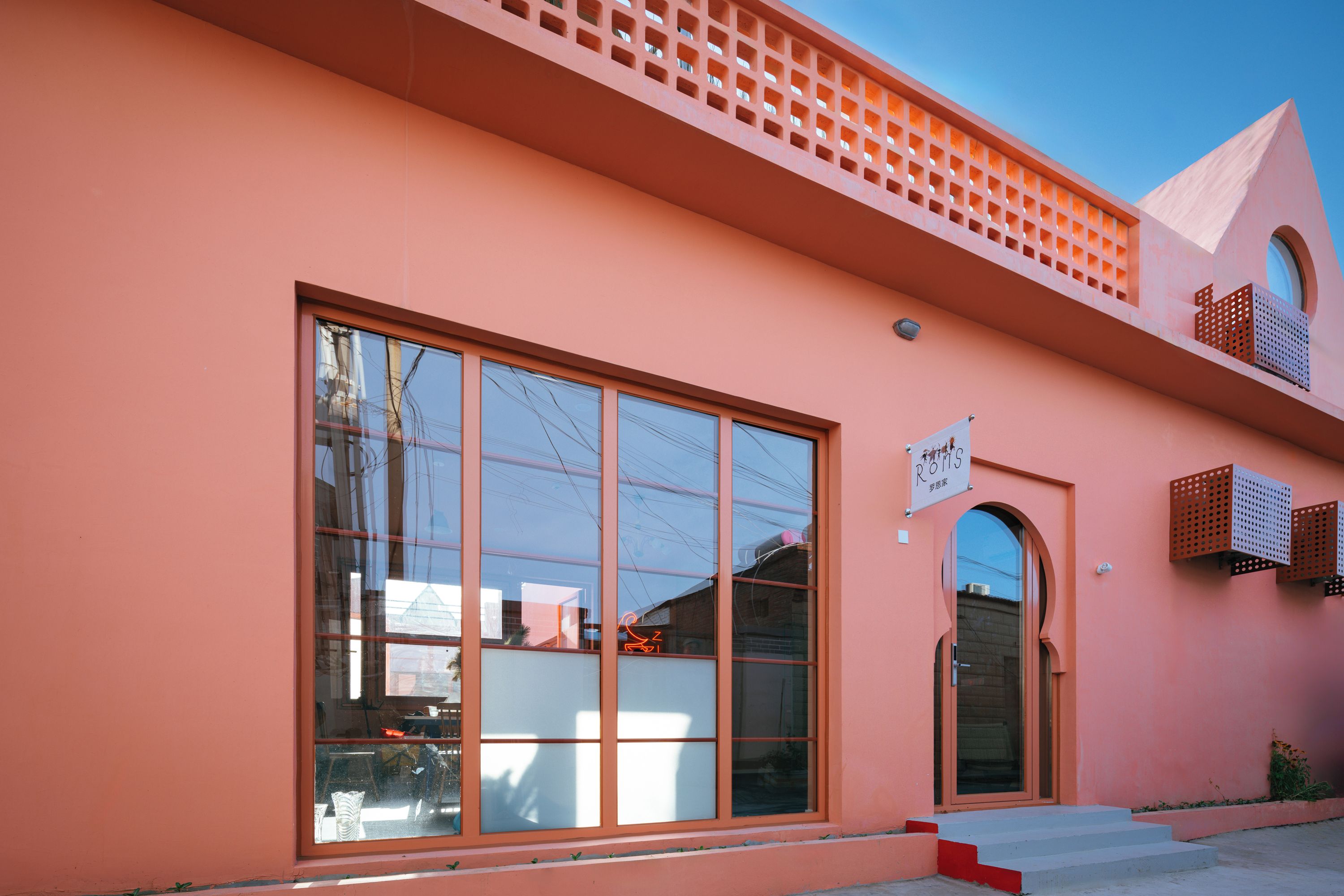 A building with large windows, a sign, and a sloped roof.