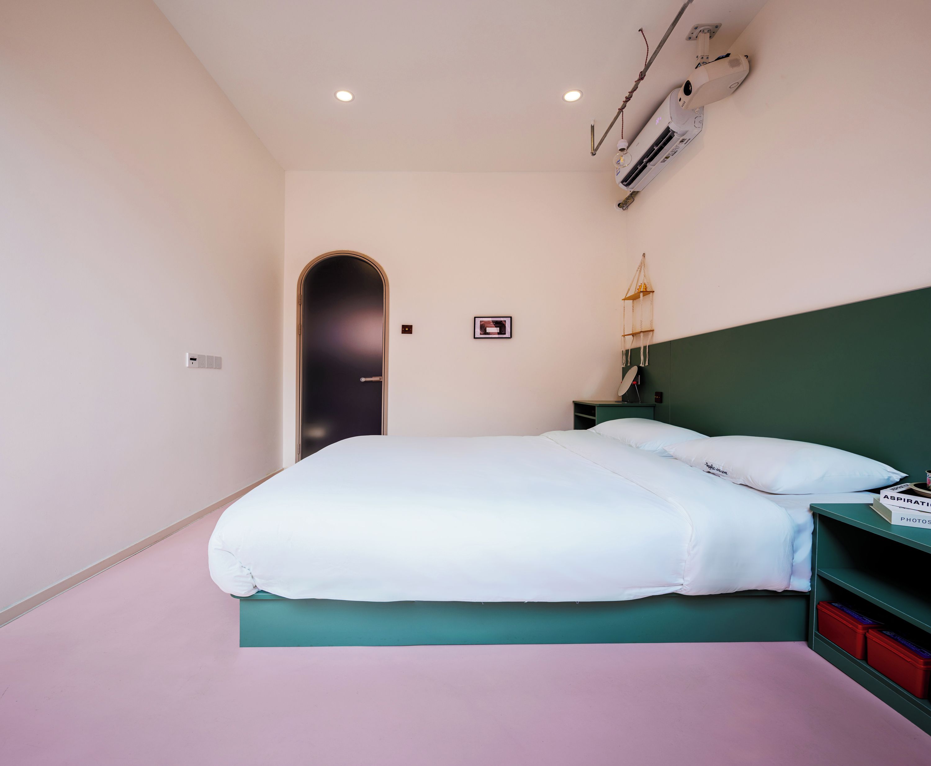 Ein Schlafzimmer mit einem Bett, einem Nachttisch, einer Wand-Klimaanlage und einer Tür.