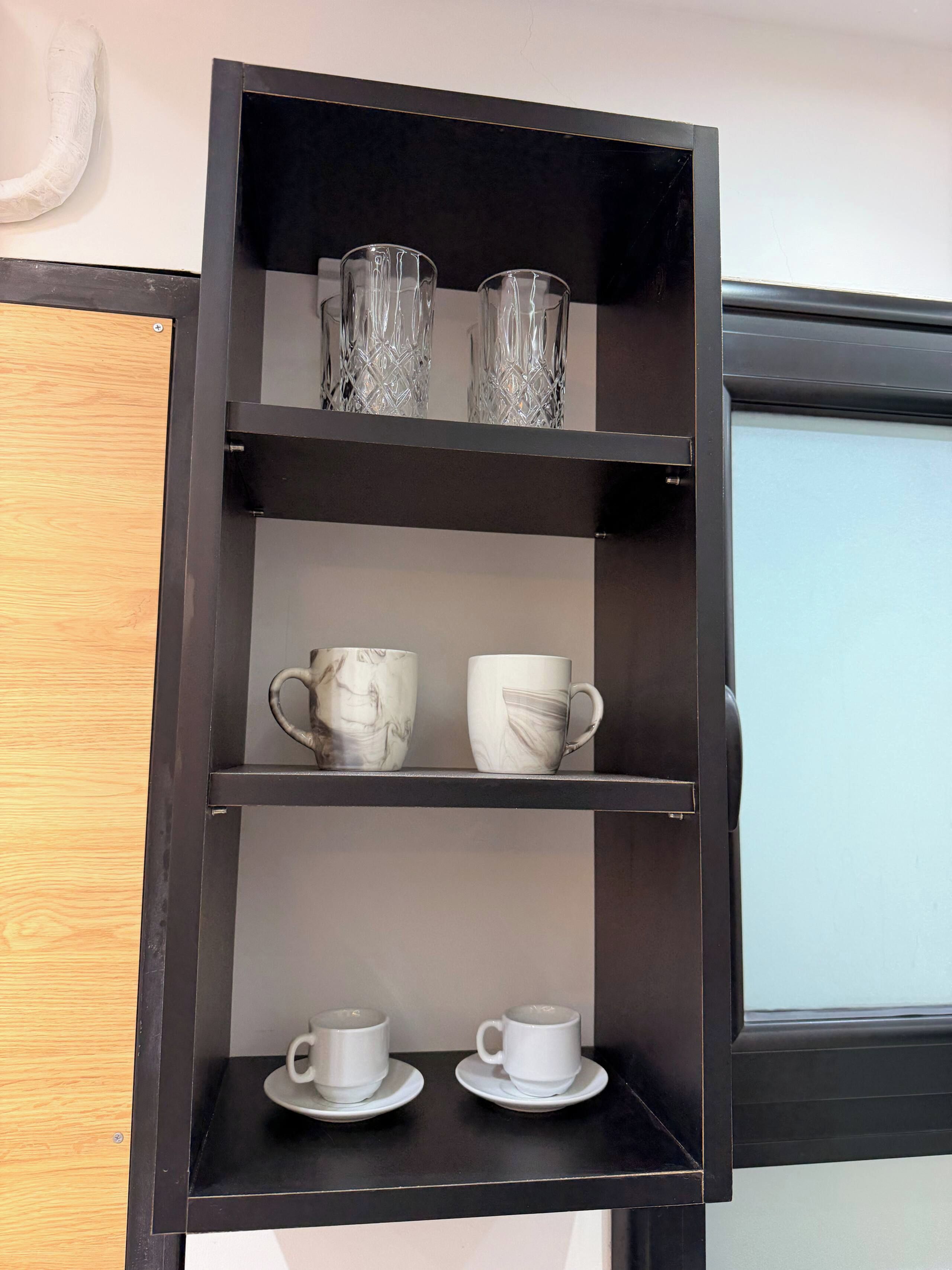A black shelf with three tiers, each holding different items.