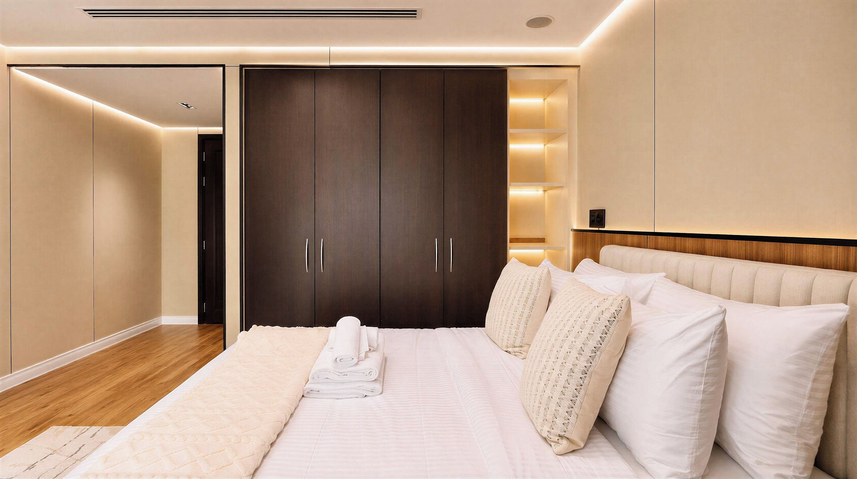 Quarto com cama grande, guarda-roupa e mesa de cabeceira.
