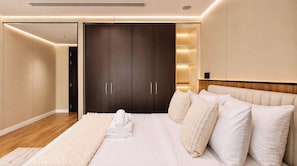 Quarto com cama grande, guarda-roupa e mesa de cabeceira.