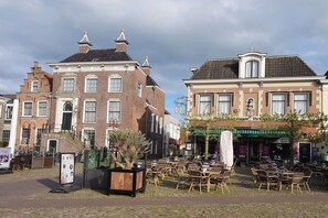 A traditional European street with brick buildings, outdoor seating, and a restaurant. - Friesland Zilverreiger 4 (JK Workum)