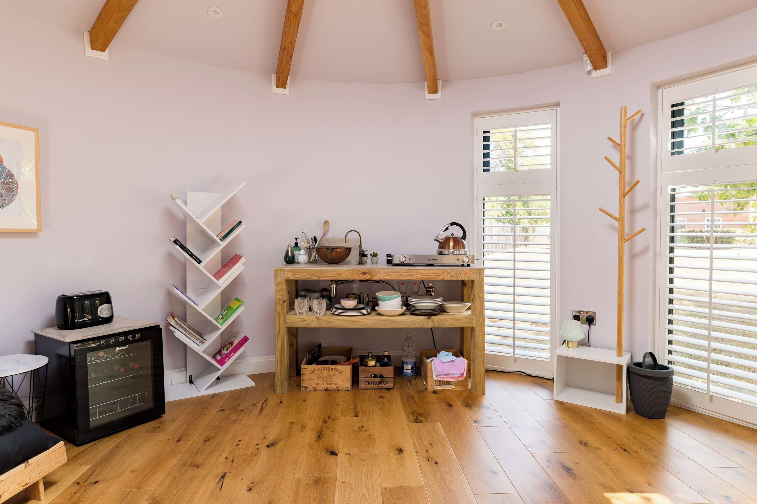 A cozy kitchen with wooden beams, a bookshelf, a kettle, and a coffee machine.