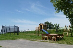 A playground with a slide, a wooden playhouse, and a picnic table. - Holiday apartment with 1 bedroom (Kressbronn)