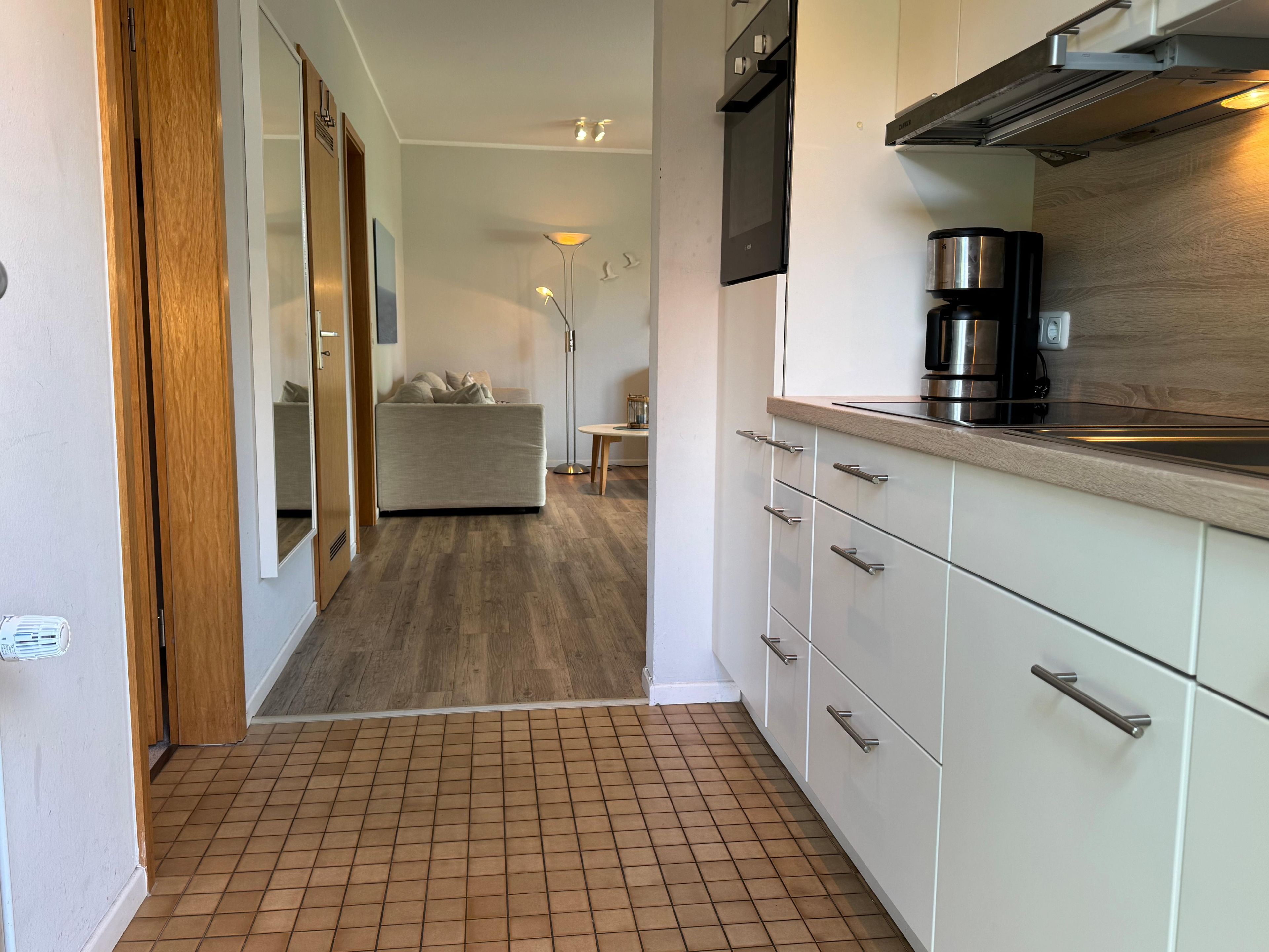 A modern kitchen with white cabinets, a coffee maker, and a microwave.