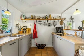 A modern kitchen with white cabinets, a wooden countertop, and a variety of kitchen utensils and appliances. - Thatched timber-framed house by meadow and stream (Balle)