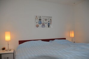 Ein Hotelzimmer mit einem Bett, zwei Nachttischlampen, einem Nachttisch und einem Bild an der Wand.
