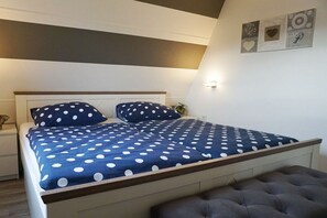 Ein Schlafzimmer mit einem Bett, einem Nachttisch, einer Wandlampe und einer Wanddekoration.