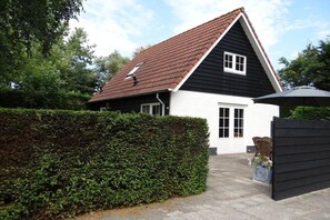 A two-story house with a sloped roof, a front door, and a small porch area. - Holiday home with 3 bedrooms (Oostkapelle)