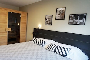 Quarto com cama, guarda-roupa de madeira e três fotografias emolduradas na parede.