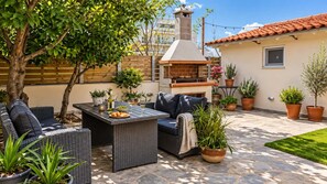 An outdoor patio area with wicker furniture, a pizza oven, and potted plants. - Secret Garden Volos - Tranquil Private Retreat (Volos)