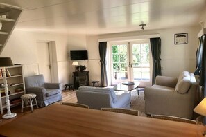 A cozy living room with a fireplace, comfortable seating, and a television. - Holiday home de Koektrommel (Domburg)