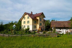 Ein zweistöckiges Haus mit rotem Dach, umgeben von einem Holzzaun und üppigem Grün.