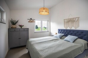 A bedroom with a bed, a wardrobe, a hanging light fixture, a window, and a macrame wall hanging. - Schottenhof Walser 3 (Achberg)