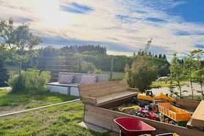A wooden bench with cushions, a wheelbarrow, and construction equipment in a grassy outdoor area. - Schottenhof Walser 3 (Achberg)