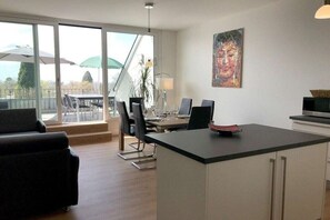 A modern kitchen with a dining area, large windows, and a view of the outdoors. - Holiday apartment with 1 bedroom (Lindau)