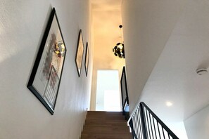 A staircase with a wooden finish, a black railing, and a light fixture with a spherical design. - Holiday apartment with 1 bedroom (Lindau)