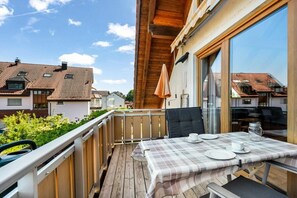 Un balcone con un tavolo apparecchiato per due persone, vista su una zona residenziale.