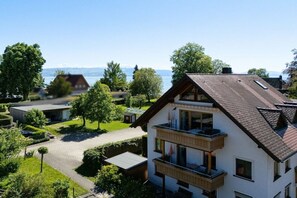 Un edificio residenziale a due piani con un balcone, circondato dal verde e con vista sul lago.
