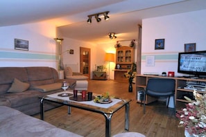 A living room with a sofa, coffee table, and a television. - Wellness holiday apartment Graf Schumann (Röhrnbach)