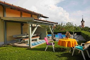 A patio area with a pool, outdoor seating, and a view of a church. - Wellness holiday apartment Graf Schumann (Röhrnbach)