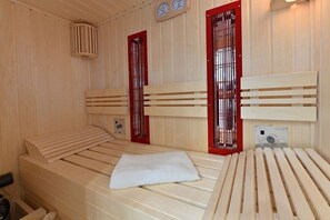 A sauna room with wooden benches and red-framed windows. - Holiday apartment in Glowe with sauna (Glowe)