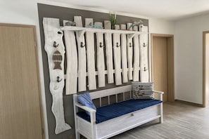 A room with a white bench, a wooden wall with a whiteboard, and a door. - Holiday home Baltic Sea love (Glowe)