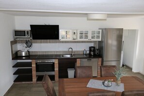 A compact kitchen with a microwave, oven, sink, and refrigerator. - Holiday home Baltic Sea love (Glowe)