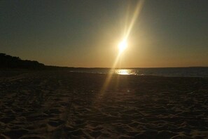 A beach with the sun setting over the horizon. - Holiday home Baltic Sea love (Glowe)