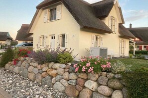 A traditional house with a stone wall and flower beds in front. - Holiday home with 2 bedrooms (Kramerhof OT Parow)