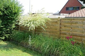 Ein Holzzaun neben einem Gartenbereich mit Rasen und einigen Blumen.