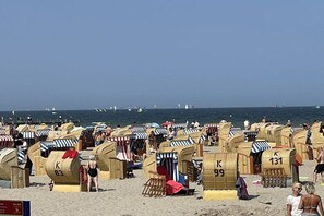 A beach with numerous wicker beach huts, some with numbers on them, and people around. - Baltic Sea Dream 139 (Travemünde)