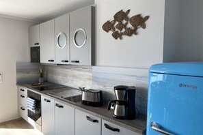A modern kitchen with grey cabinets, a blue refrigerator, and a coffee maker. - Baltic Sea Dream 139 (Travemünde)