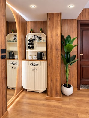 A wooden interior with a coffee-themed cabinet, a potted plant, and a door. - 3BRs Mohandessin Modern Living (Giza Governorate)