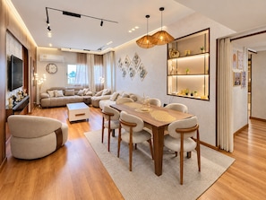 A modern living room with a wooden dining table, sofas, and a TV. - 3BRs Mohandessin Modern Living (Giza Governorate)