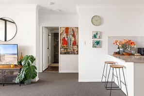 A modern kitchen with a clock, bar stools, and a view to the dining area. - Spacious 2-Bed Apartment Near Parramatta CBD (Parramatta)