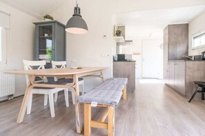 Eine moderne Küche mit Essbereich, Holzmöbeln und einer Pendelleuchte.