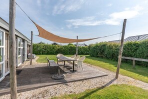 Eine Terrasse im Freien mit Tisch und Stühlen, umgeben von einer Holzdielenveranda und Kies.