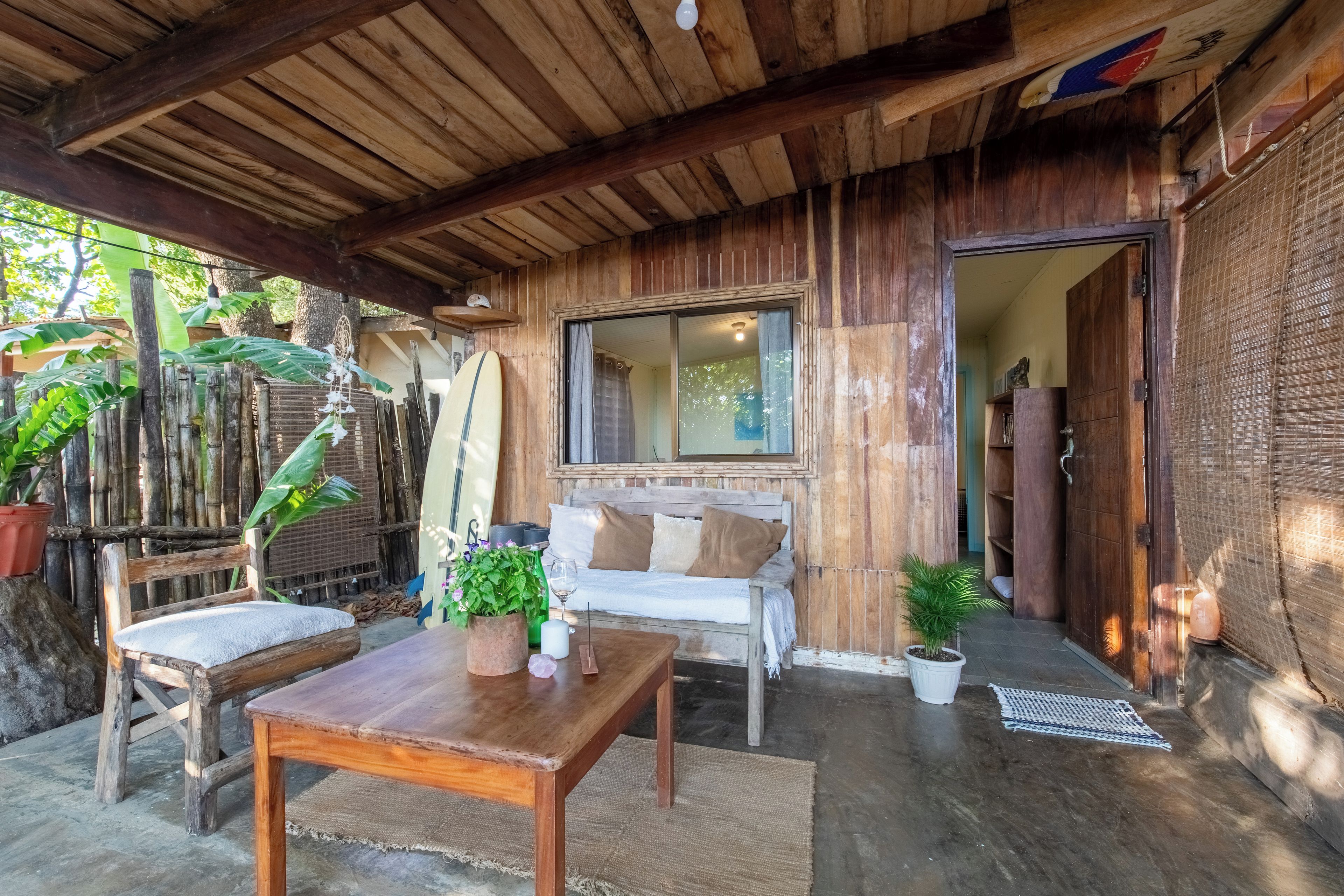 Una cabaña de madera con una mesa, dos sillas, un banco y una ventana.