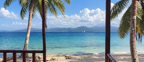 A covered beach area with a view of the ocean and palm trees.